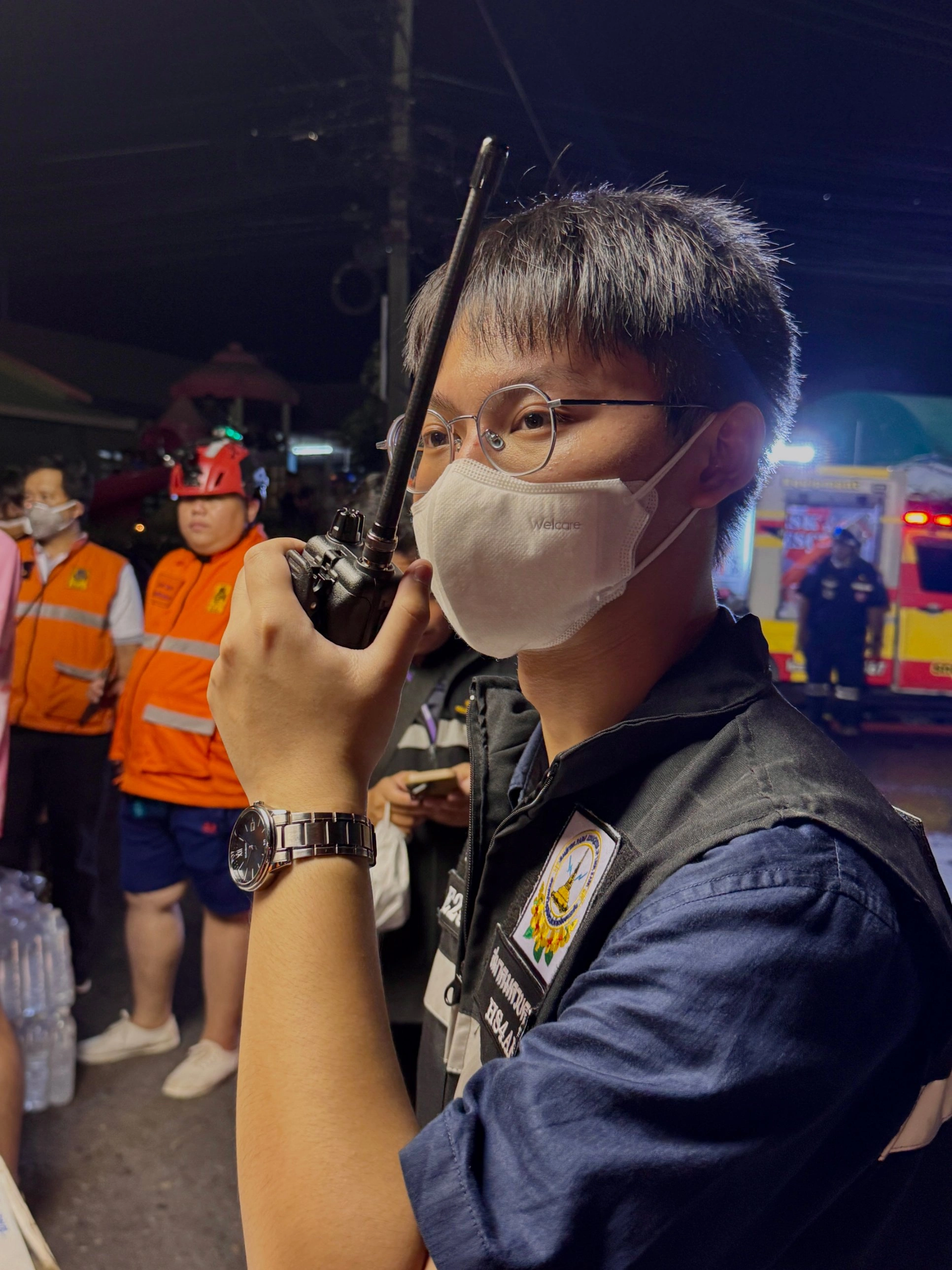 Watanyoo Putta using a handheld radio at a night emergency scene