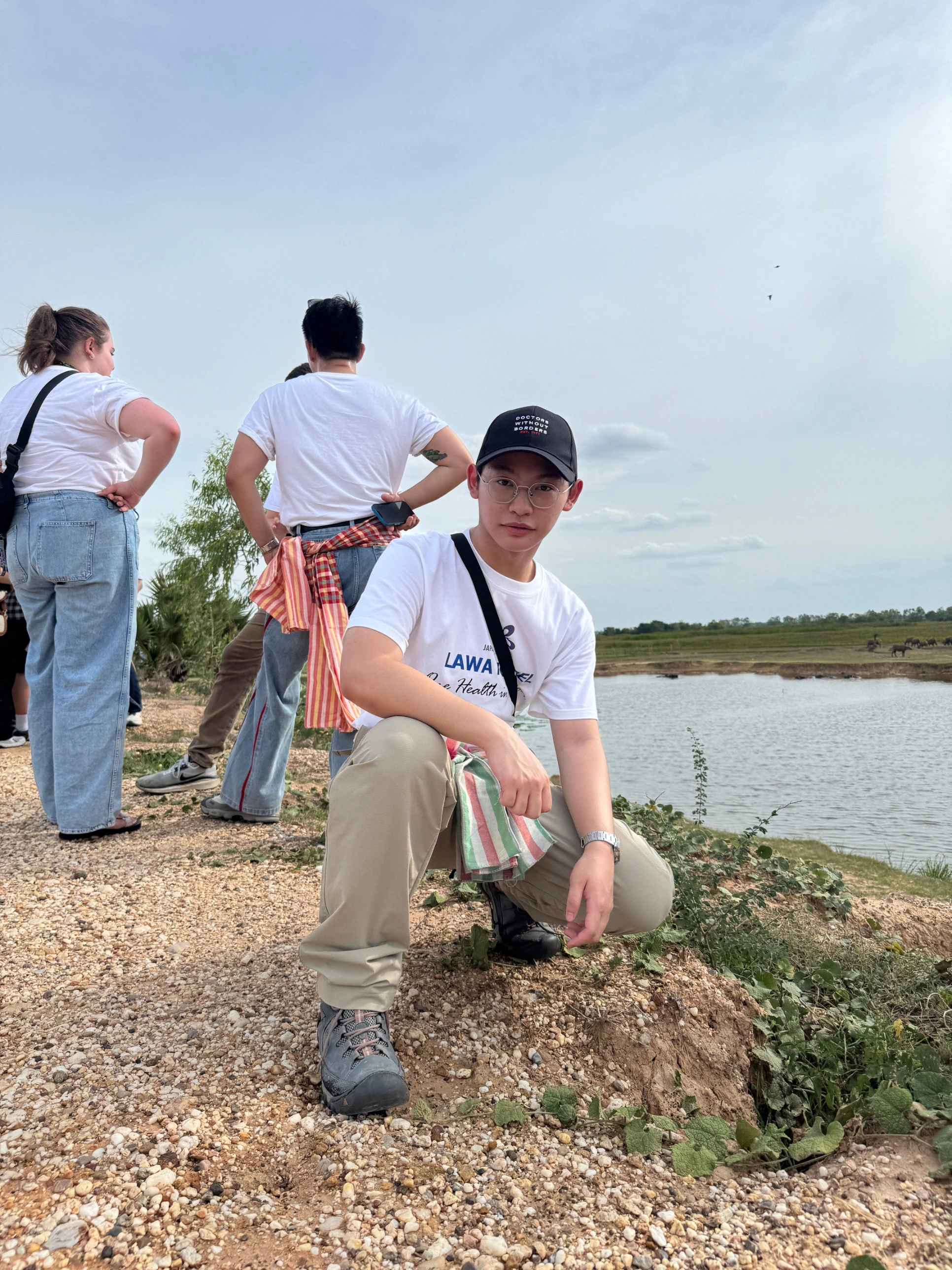 Watanyoo Putta crouching beside a lake during the Lawa Model field visit