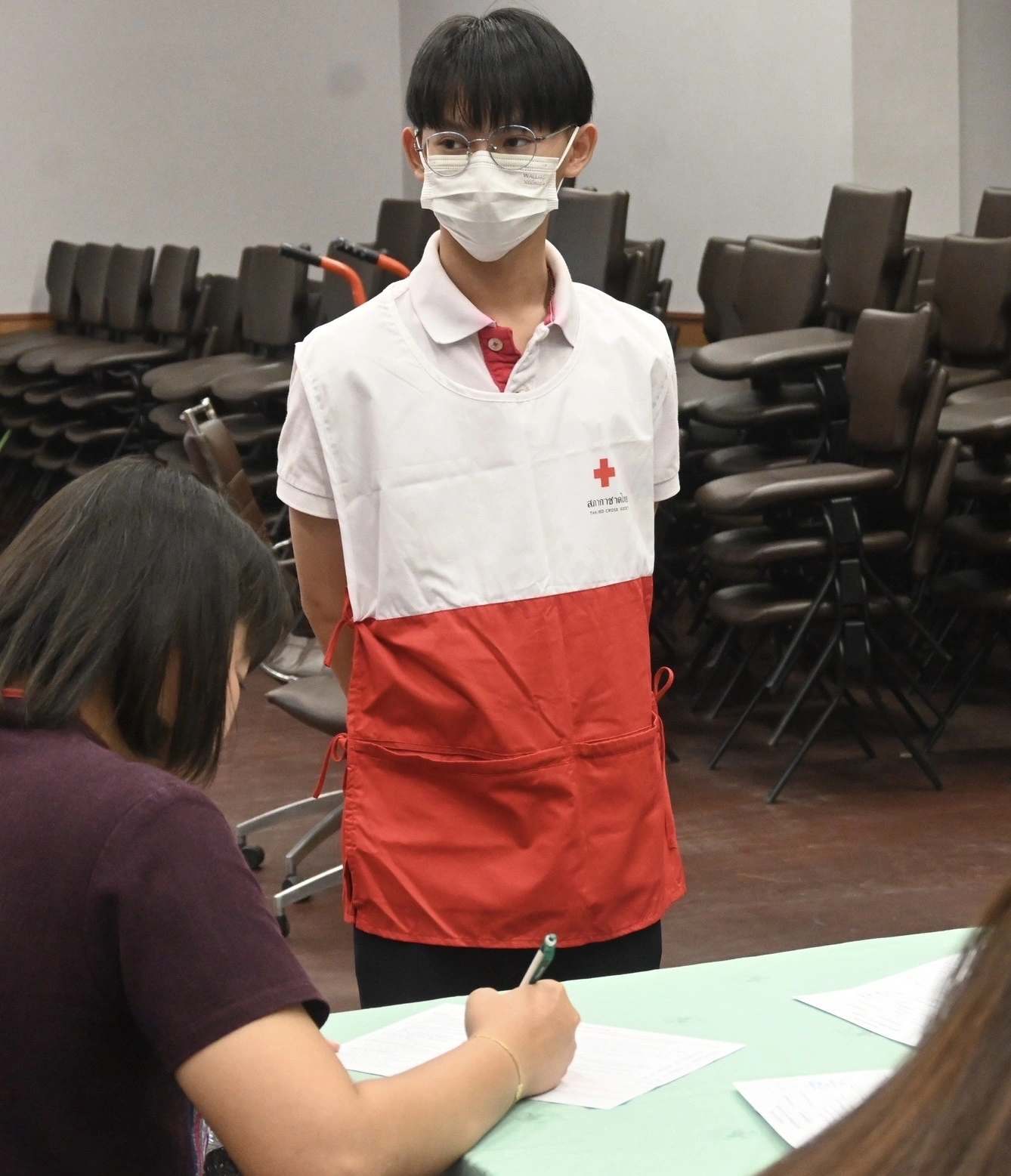Watanyoo Putta in a Thai Red Cross volunteer apron at a registration table